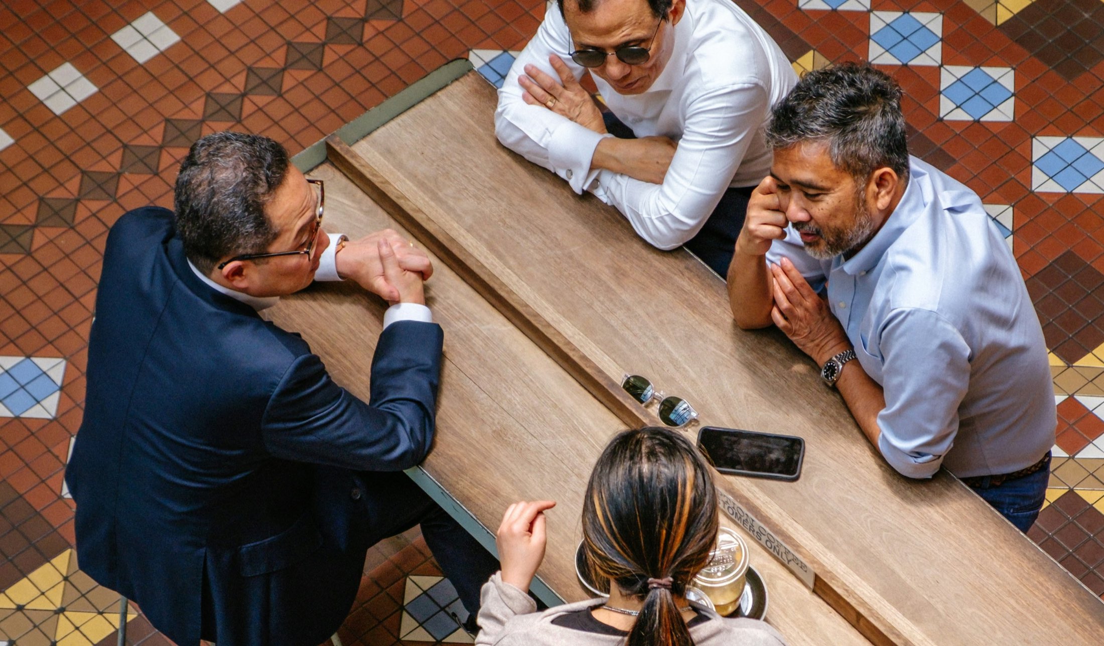 Four colleagues gathered around a long wooden table in a meeting