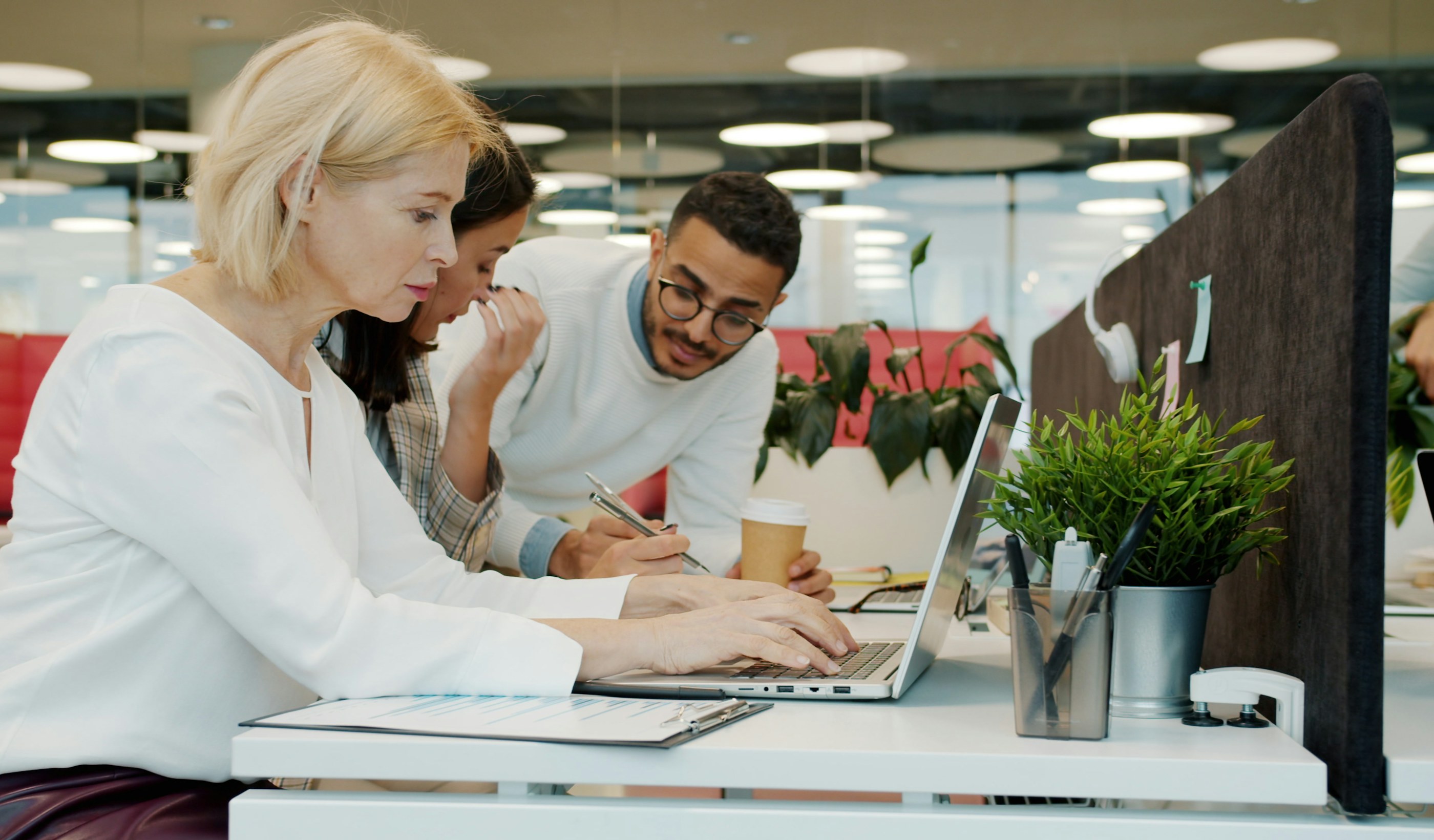 Three colleagues working through data together on a laptop in an office
