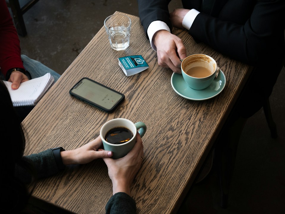 Two people talking over coffee at a wooden table