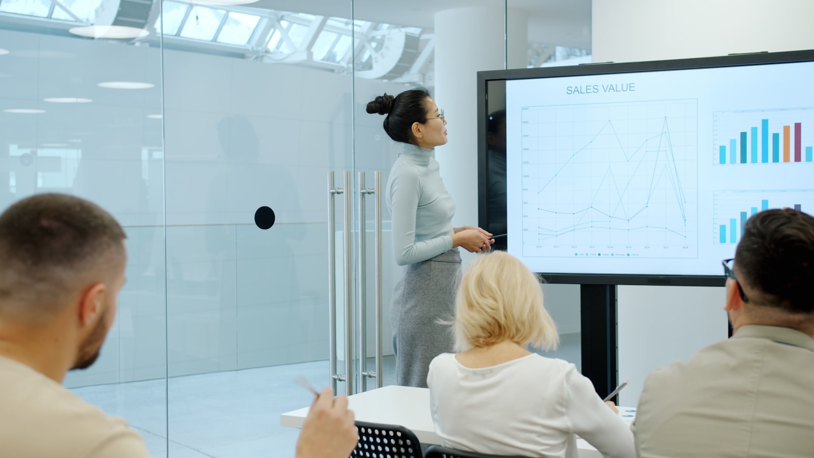 A businesswoman presenting charts on a screen to colleagues in a meeting